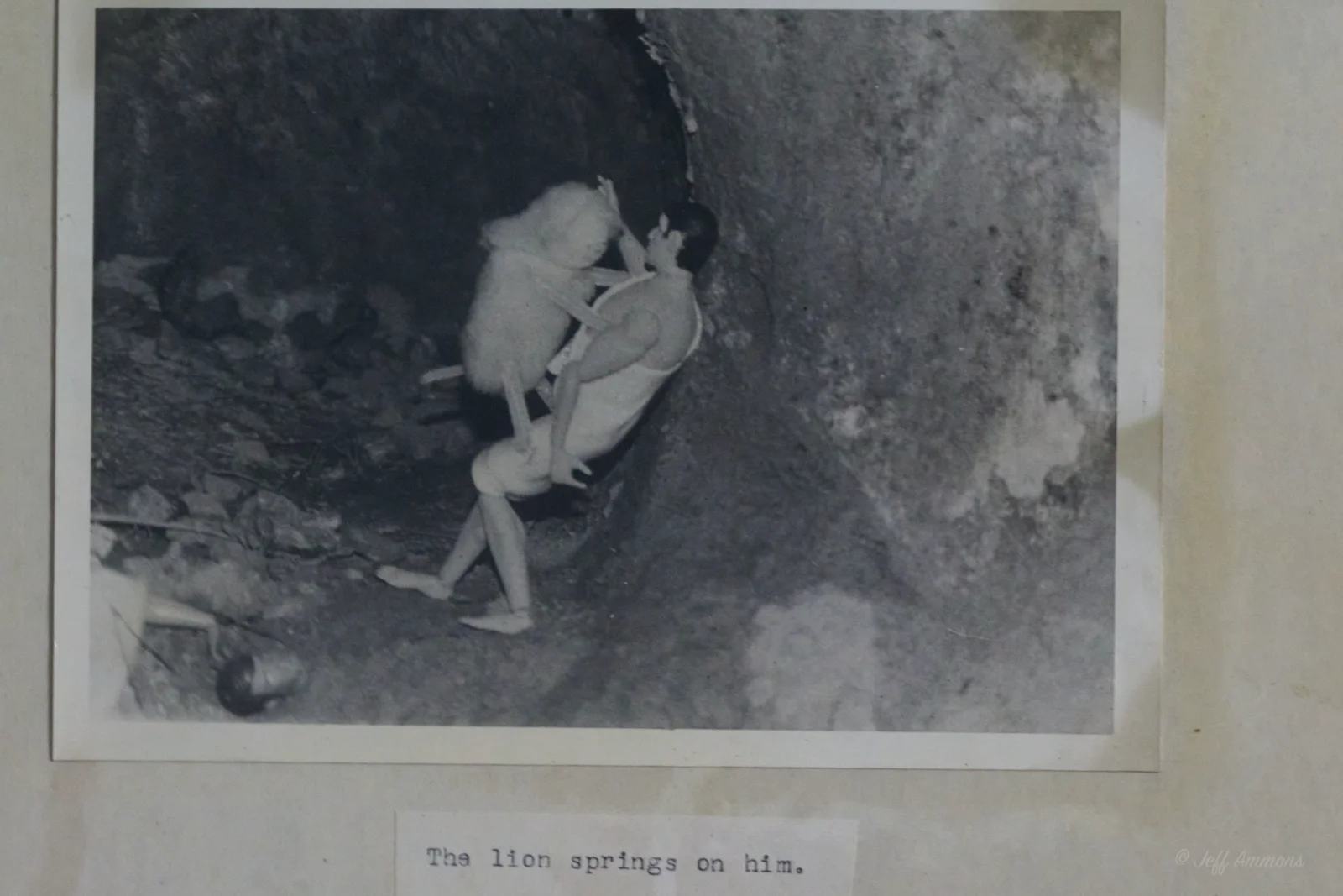 The lion springs onto Heracles inside the cave, its paws on his shoulders.